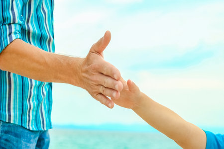beautiful hands of a happy parent and child by the sea in nature