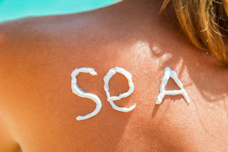 happy girl on the sea with a picture of the sun on her backの写真素材