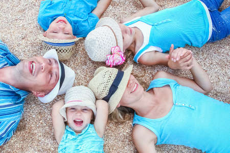 Happy family playing by the sea shore on the sand backgroundの写真素材