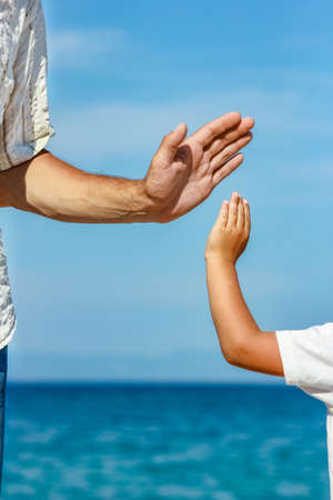happy dad holds the hand of a child by the greek sea in natureの写真素材