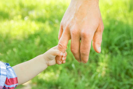 the parent holding the child's hand with a happy backgroundの写真素材