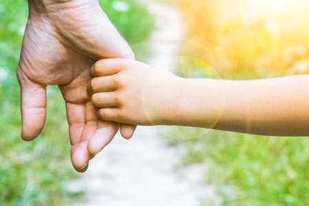 the parent holding the child's hand with a happy backgroundの写真素材