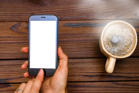 Female hands holding cup of coffee on wooden backgroundの写真素材