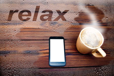 coffee with phone through glass with drops on a wooden backgroundの写真素材