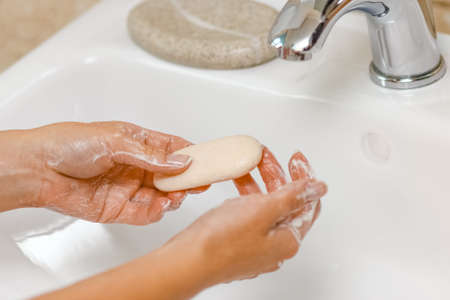 Washing hands with soap under the faucet with waterの写真素材