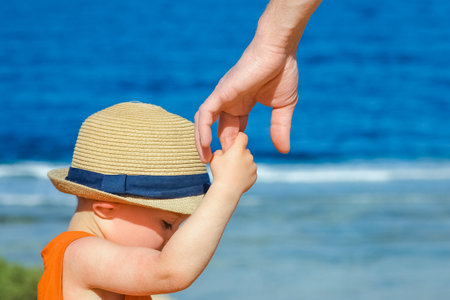 Hands of child and parent on vacation by the sea background.の写真素材
