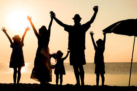 Happy family by the sea at sunset in travel silhouette in natureの写真素材