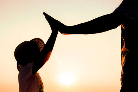 Hands of happy father and child by the sea on nature silhouette travelの写真素材