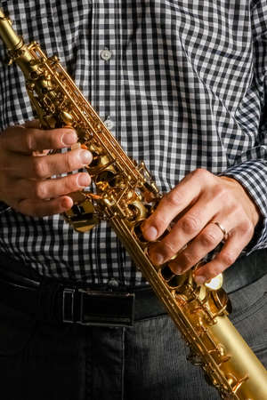 soprano saxophone in hands on a black backgroundの写真素材