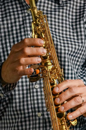 soprano saxophone in hands on a black backgroundの写真素材