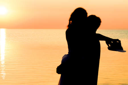 Happy couple by the sea at sunset on travel silhouette in natureの写真素材