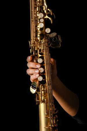soprano saxophone in hands on a black backgroundの写真素材