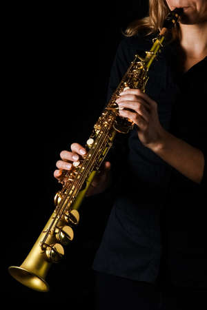 soprano saxophone in hands on a black backgroundの写真素材