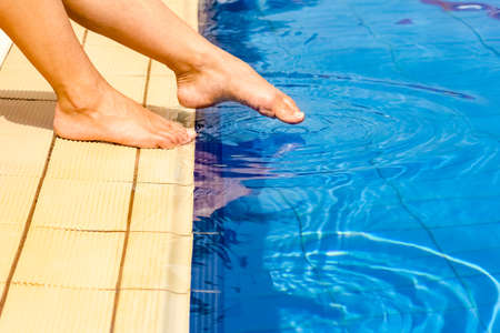 beautiful legs of a girl near a swimming pool on the sea background