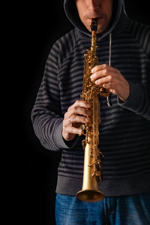 soprano saxophone in the hands of a guy on a black backgroundの写真素材