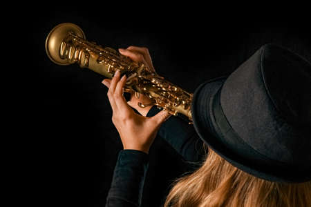 soprano saxophone in the hands of a girl on a black background