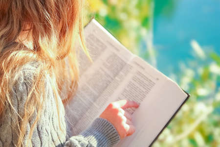 Happy child reading book on nature education in park travel