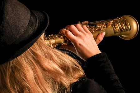 soprano saxophone in the hands of a girl on a black backgroundの写真素材