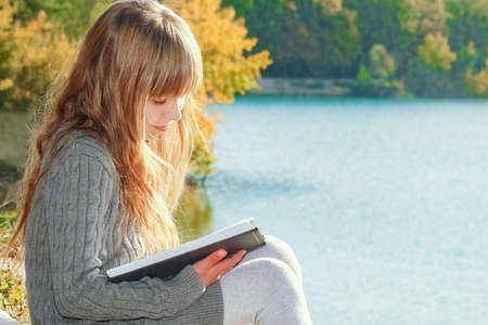 Happy child reading book on nature education in park travel