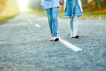 Happy parent with child are walking along the road in the park on nature travel