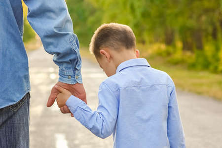 Happy parent with a child in the park hands on nature travel go along the roadの写真素材
