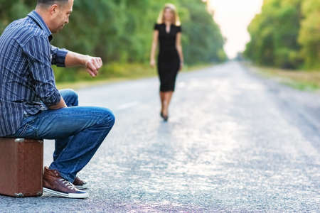 Happy couple with suitcase on road path in park on nature travelの写真素材