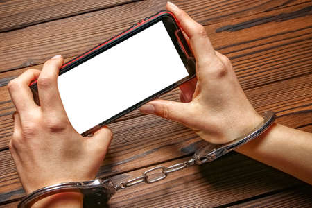 phone with hands addiction on a wooden backgroundの写真素材