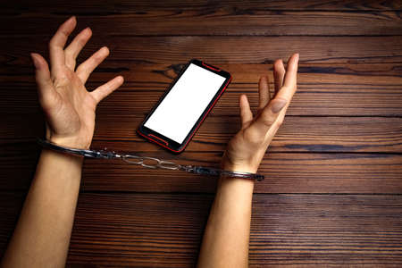 phone with hands addiction on a wooden backgroundの写真素材