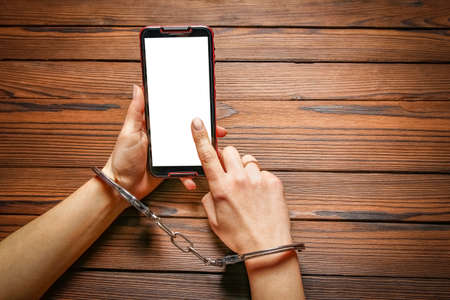 phone with hands addiction on a wooden backgroundの写真素材