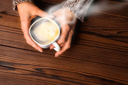 female hands and coffee on wooden backgroundの写真素材