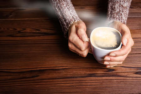 female hands and coffee on wooden background