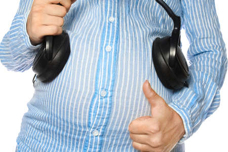 Happy pregnant girl with headphones in hands in hands on a white background. Positive music for the child.の写真素材