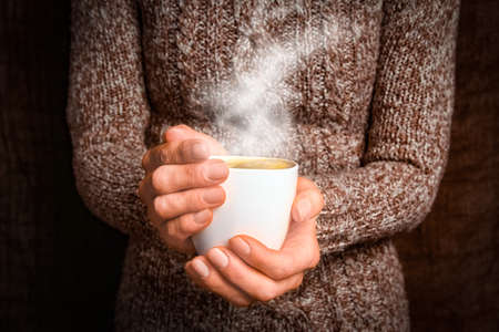 female hands and coffee on wooden backgroundの写真素材