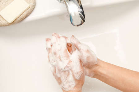 Washing hands with soap under the faucet with waterの写真素材