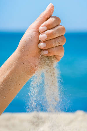 Hands pour sand off the sea on nature on a journey. Vacations at sea sand time passes.の写真素材