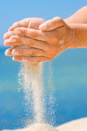 Hands pour sand from the sea to nature on a journey. Vacations on the sea sand time passes. Business time.の写真素材