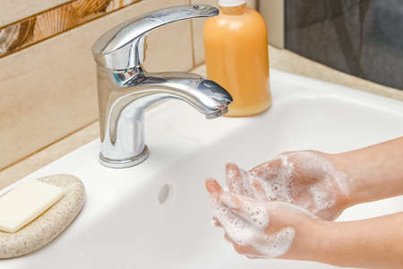 Washing hands with soap under the faucet with water
