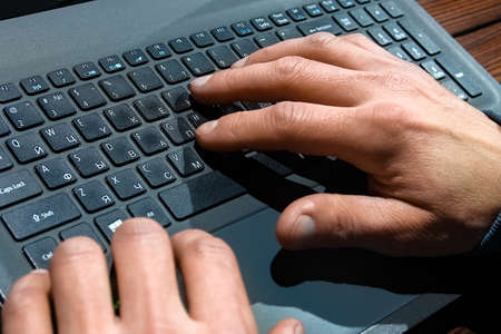 Hacker with computer man sitting at a table in a hood