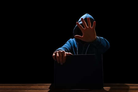 Hacker with laptop sits at a table and abstract binary code. Business life threat virtual programs.の写真素材