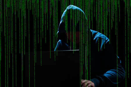 Hacker with laptop and abstract binary code.