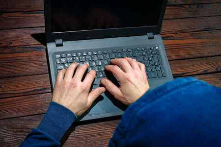 Hacker with laptop sits at a table and abstract binary code. Business life threat virtual programs.