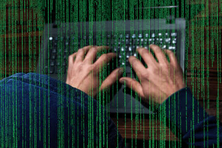 Hacker with laptop and abstract binary code.