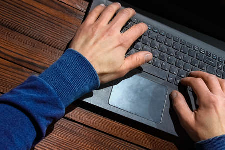 Hacker with computer man sitting at a table in a hoodの写真素材