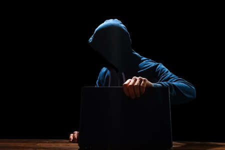 Hacker with laptop sits at a table and abstract binary code. Business life threat virtual programs.の写真素材