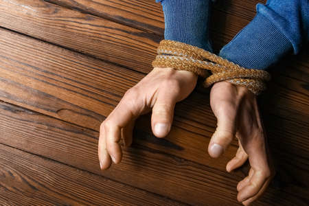 hands with a rope on a wooden background
