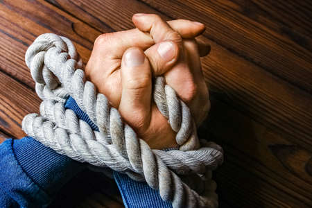 hands with a rope on a wooden backgroundの写真素材