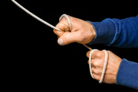 Hands with a rope on a black background. A man pulls a sports rope.の写真素材