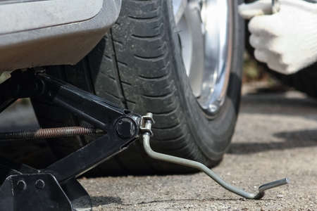 After a breakdown, a person changes a wheel on a car to another wheel with a wrench