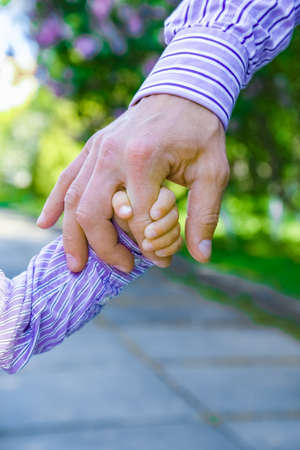 the parent holding the child's hand with a happy backgroundの写真素材