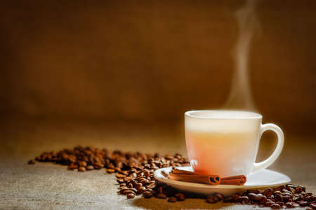 Coffee cup and coffee beans on a wooden table and sack background, Vintage color tone